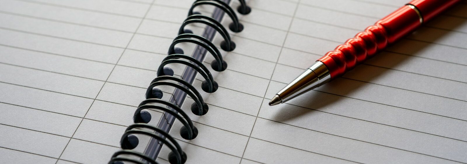 a red pen sitting on top of a notebook